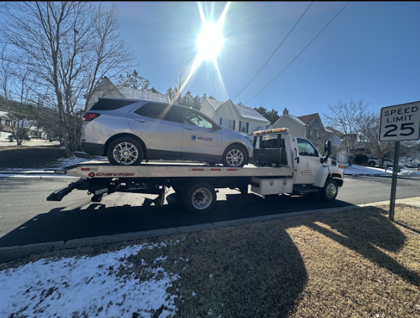 Winter towing of a silver SUV on a snowy residential road