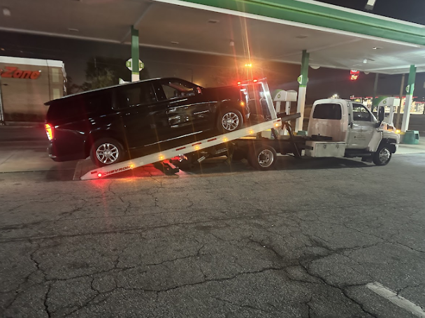 Nighttime emergency towing of a black SUV at a gas station by Classic Towing