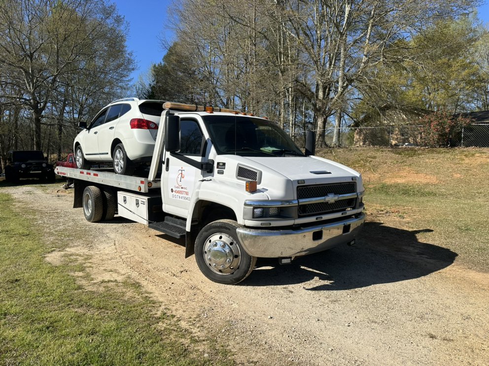 Classic Towing flatbed hauling a white SUV on a rural property